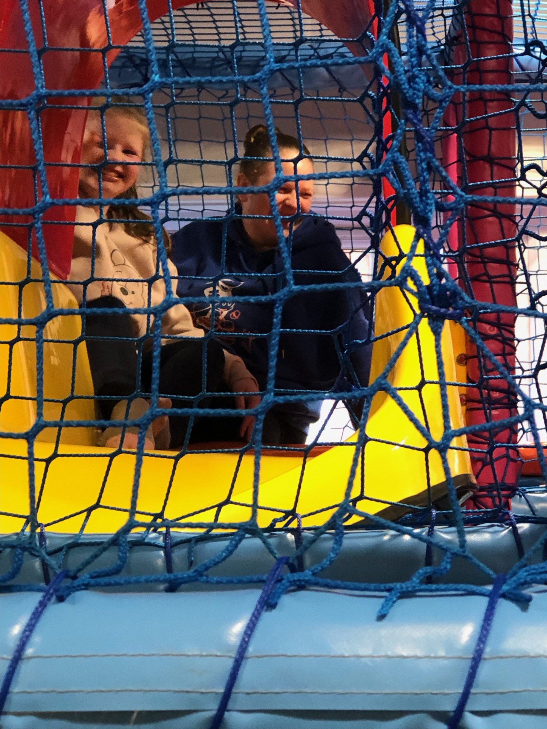 Daniela and her mum at the top of the soft play slide, smiling